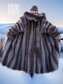 Back view of long dark brown hooded fur coat with raised hood and flared shoulders.