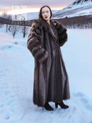 Long dark brown hooded fur coat with draped front and full-length sleeves.