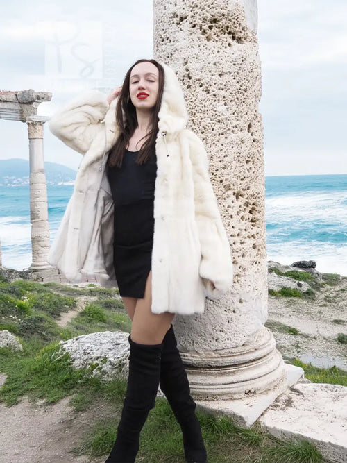 Women’s mink fur hooded coat, light beige, front view over a black dress and boots