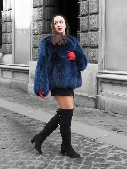 Blue fox-fur jacket with hood and long sleeves, worn over a short black dress.