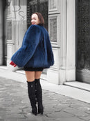 Vibrant blue faux fur jacket with rounded shoulders and long sleeves, side view
