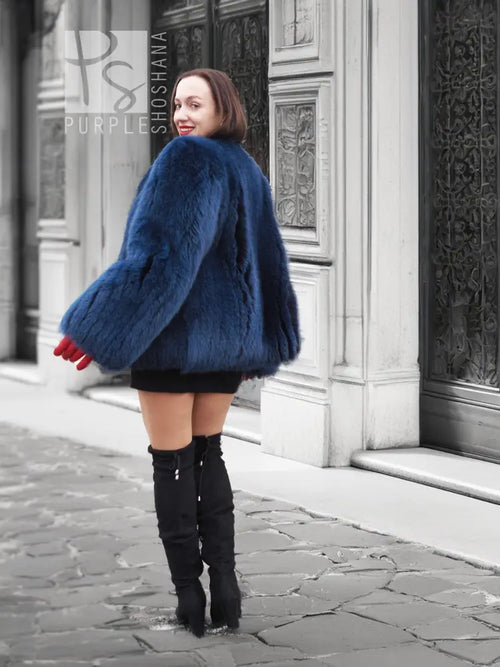 Vibrant blue faux fur jacket with rounded shoulders and long sleeves, side view