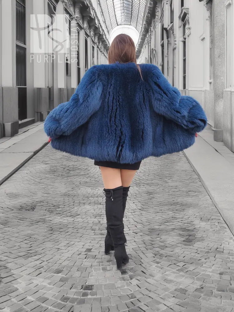 Back view of blue fox-fur hooded jacket with flared hem and long sleeves.