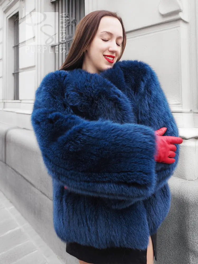 Blue fox-fur jacket with plush texture and hood, long sleeves with ribbed cuffs.