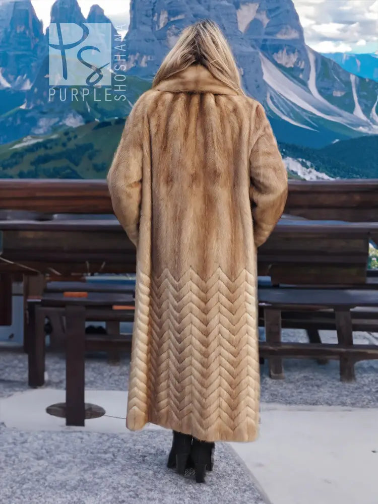 Back view of tan mink fur coat with hood and herringbone pattern at the hem.