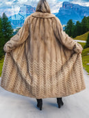 Hooded tan mink fur coat with wide flared skirt and herringbone pattern on the back.