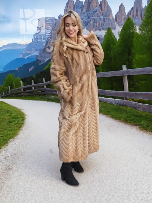 Long tan mink fur coat with hood, chevron/herringbone pattern, front button closure.