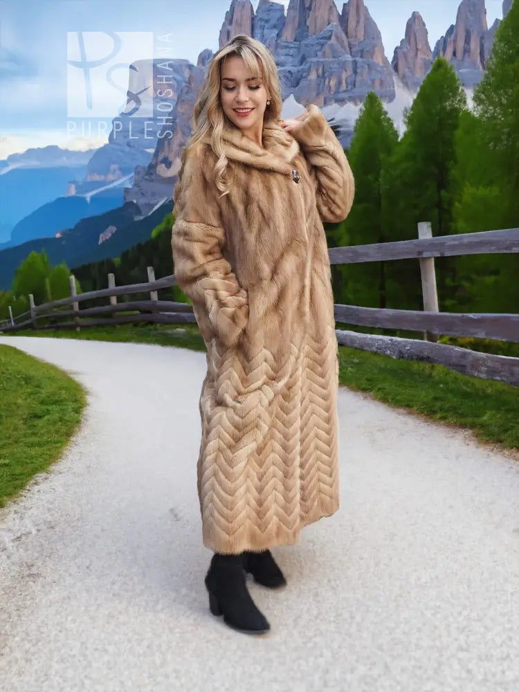 Long tan mink fur coat with hood, chevron/herringbone pattern, front button closure.