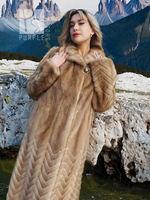 Long tan mink fur coat with chevron pattern and buttoned neck detail.
