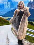 Tan mink fur coat with hood, long length, and herringbone pattern worn over black top.