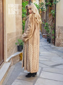 Tan mink fur coat with hood, long skirt, and herringbone textured pattern down the front.