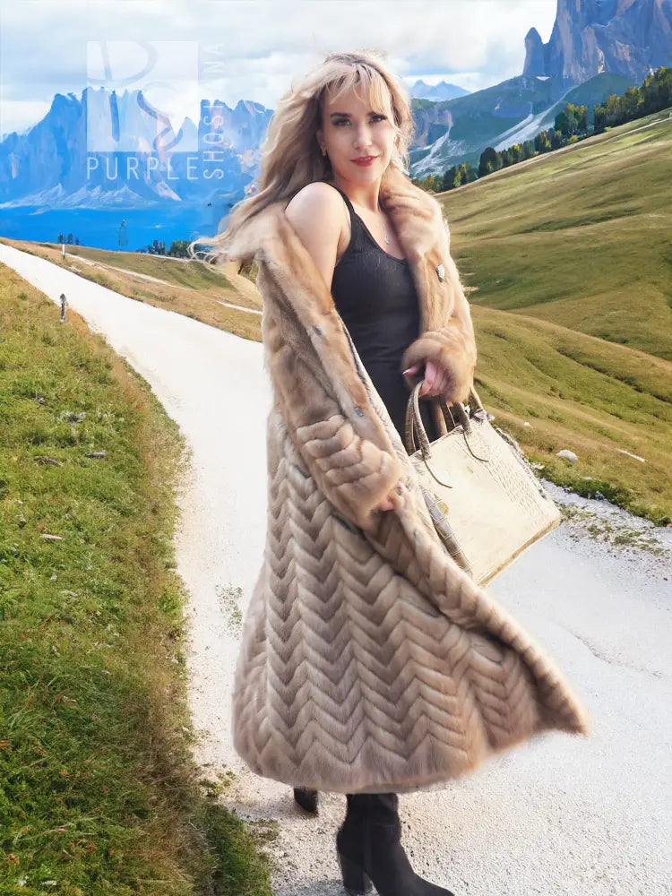 Pastel tan mink fur coat with hood and herringbone panel design, long mid-calf length.