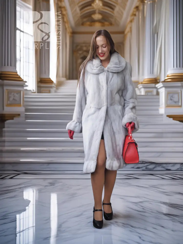 Light gray mink coat with petal collar and flared sculpted hem, styled open with red handbag.