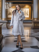 Light gray mink coat with petal collar and sculpted hem, worn front-facing with black heels.