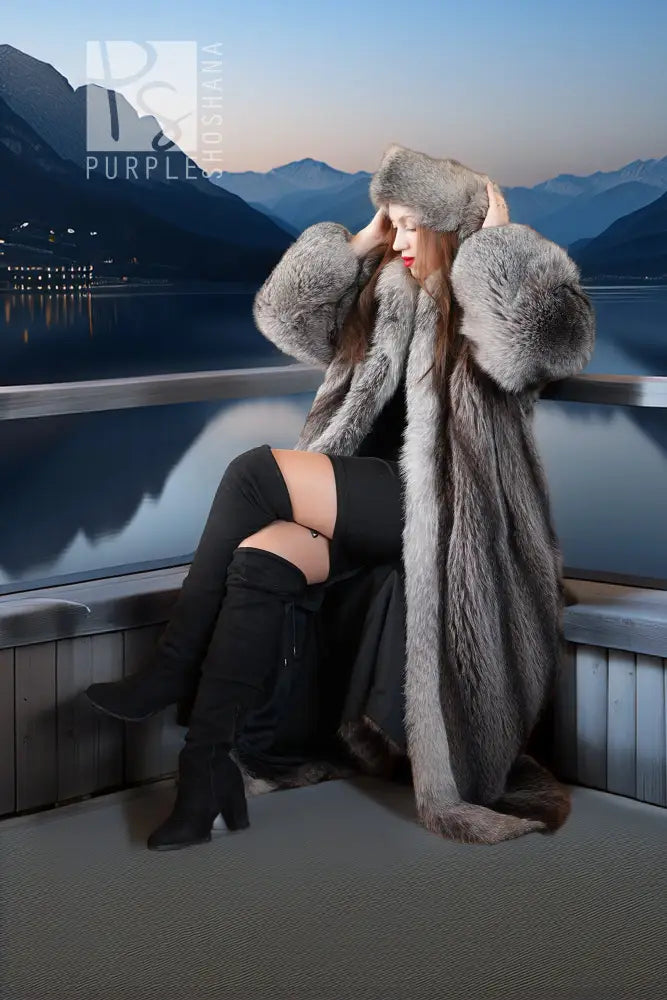 Gray raccoon fur coat with large hood and voluminous sleeves; model seated