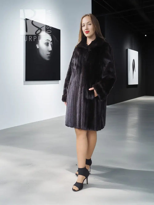 Reversible mink coat in dark, full-length with button placket and fur trim.
