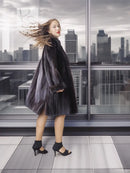 Reversible mink coat with dark fur body and long sleeves, full-length side stance.