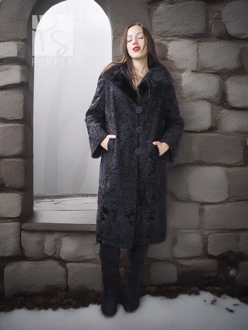 Dark lamb fur coat with fur collar, full-length front view against stone wall