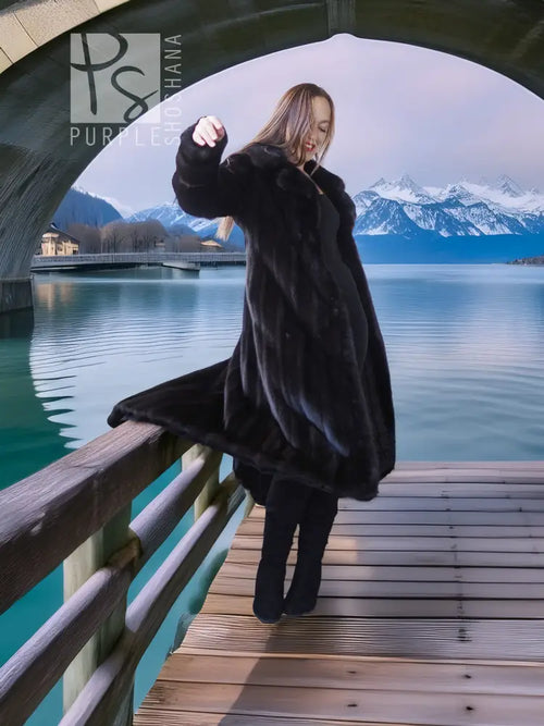Black mink long coat with broad sleeves and matching beret, shown on a wooden walkway