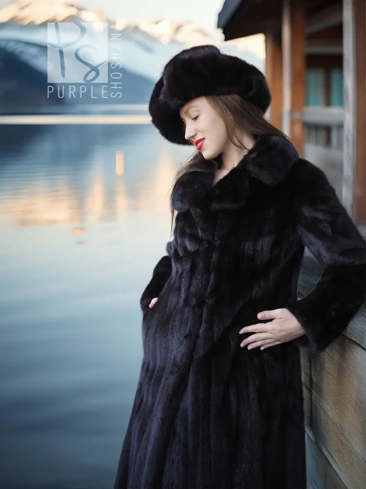 Black mink coat with wide collar and side button closure, paired with a black beret