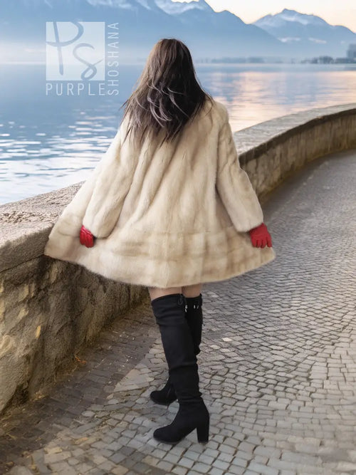 Cream faux fur coat with red cuffs and full length swing hem, worn with black boots