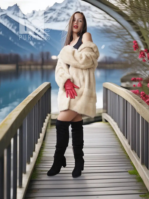 Cream faux mink fur coat with red cuff details, worn with black knee-high boots