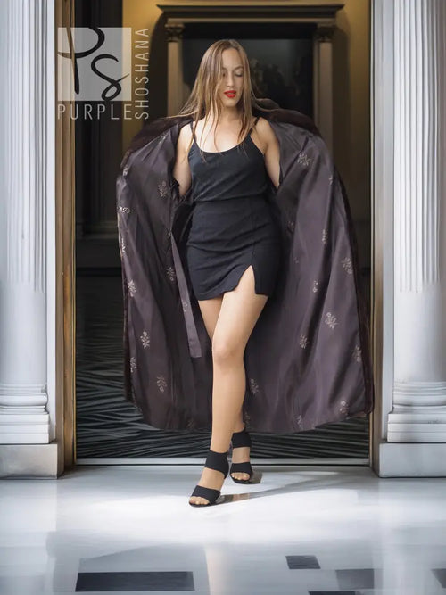 Long mahogany mink fur coat with wide sleeves, draped open over a black dress.