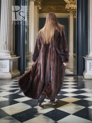 Long mink fur coat in dark brown, back view with flowing hem and voluminous sleeves