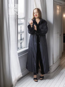 Black mink coat with button closure and wide sleeves, worn over a dark dress