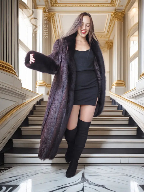 Long dark fur coat worn over a black mini dress with matching tall boots and gloves