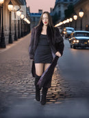 Long dark fur coat draped over a short black dress, worn with tall boots