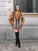 Fox-fur style jacket with orange-brown shoulders and gray panels, paired with black boots.