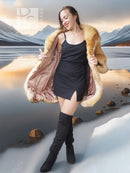 Tan-gold shaggy fur shrug coat with open front and wide sleeves over a black sleeveless dress