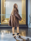 Tan-brown mink swing coat with wide collar and flared sleeves, side view.