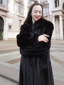 Black mink coat with thick fur sleeves and high collar framing the face