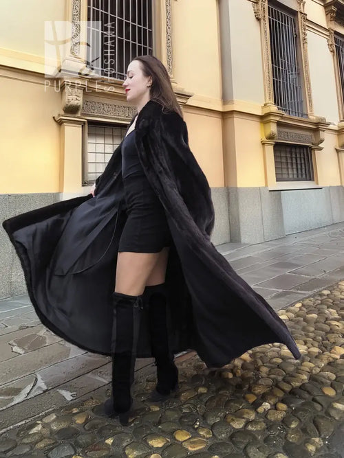 Black mink sweep coat with wide sleeves and long flowing hem, styled over boots