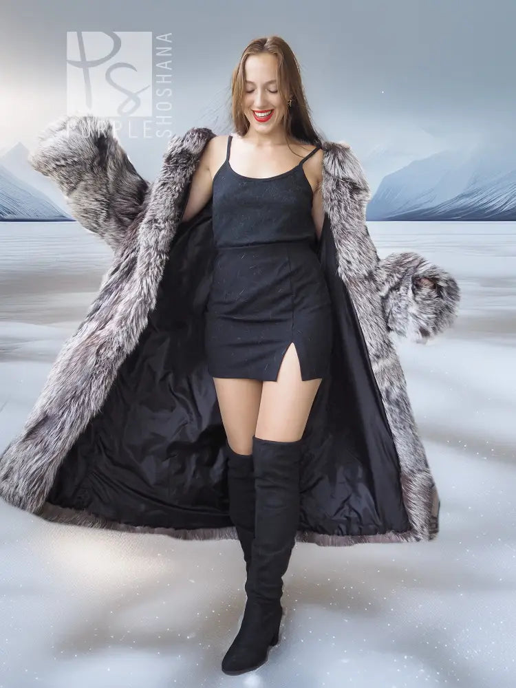Gray faux fur wrap or stole with long sleeves over a black dress and boots.