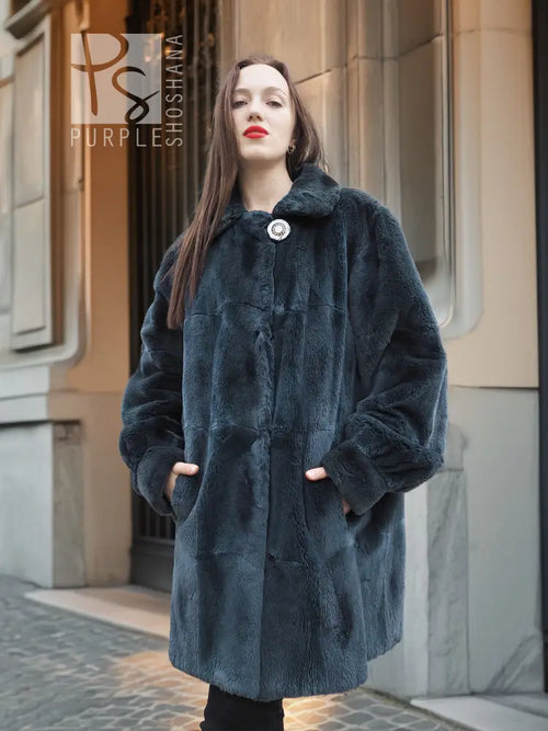 Sheared muskrat fur coat in dark teal, front view with stand collar and snap closure