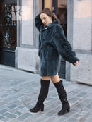 Deep teal sheared muskrat fur coat with front button and relaxed fit, angled front view
