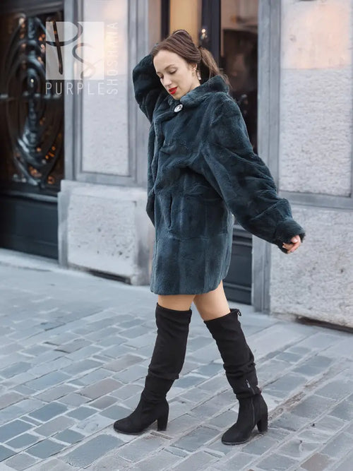 Deep teal sheared muskrat fur coat with front button and relaxed fit, angled front view