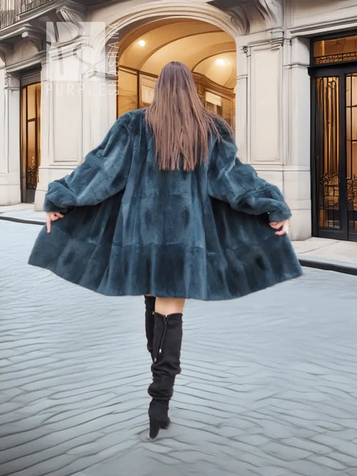 Deep teal muskrat fur coat with flared skirt shape and long sleeves, back view