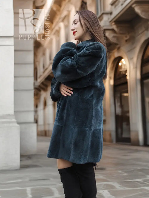 Sheared muskrat fur coat in dark teal, rear view with stand collar and snap front