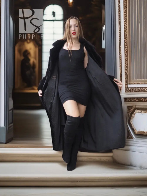 Black sheared beaver fur coat with stand collar; open front over black dress, hand extended.