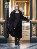 Black sheared beaver fur coat with stand collar; open front over black dress, full-body.