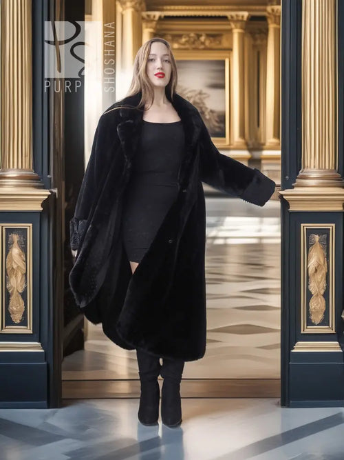 Black sheared beaver fur coat with stand collar; open front over black dress, full-body.