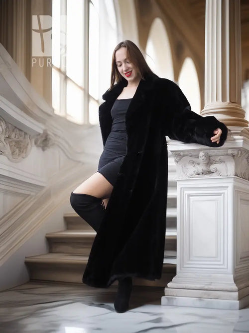 Black fur coat draped open over a dark dress, long sleeves and hem