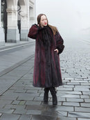 Long hooded mink fur coat, black and burgundy vertical panels, side profile