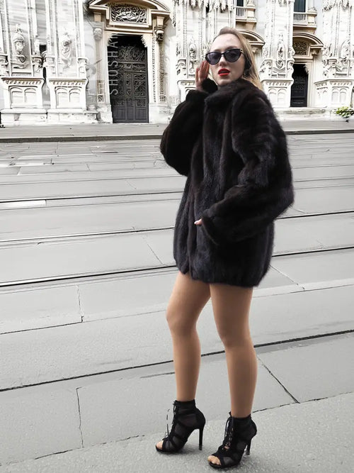 Dark mink fur bomber jacket with short hem, cozy stand collar, and curved pocket area.