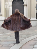 Back view of dark brown fur coat with full flare and rounded cape-like shoulders.