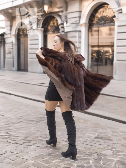 Dark brown fur coat with scalloped fur trim on shoulders, paired with black mini dress.